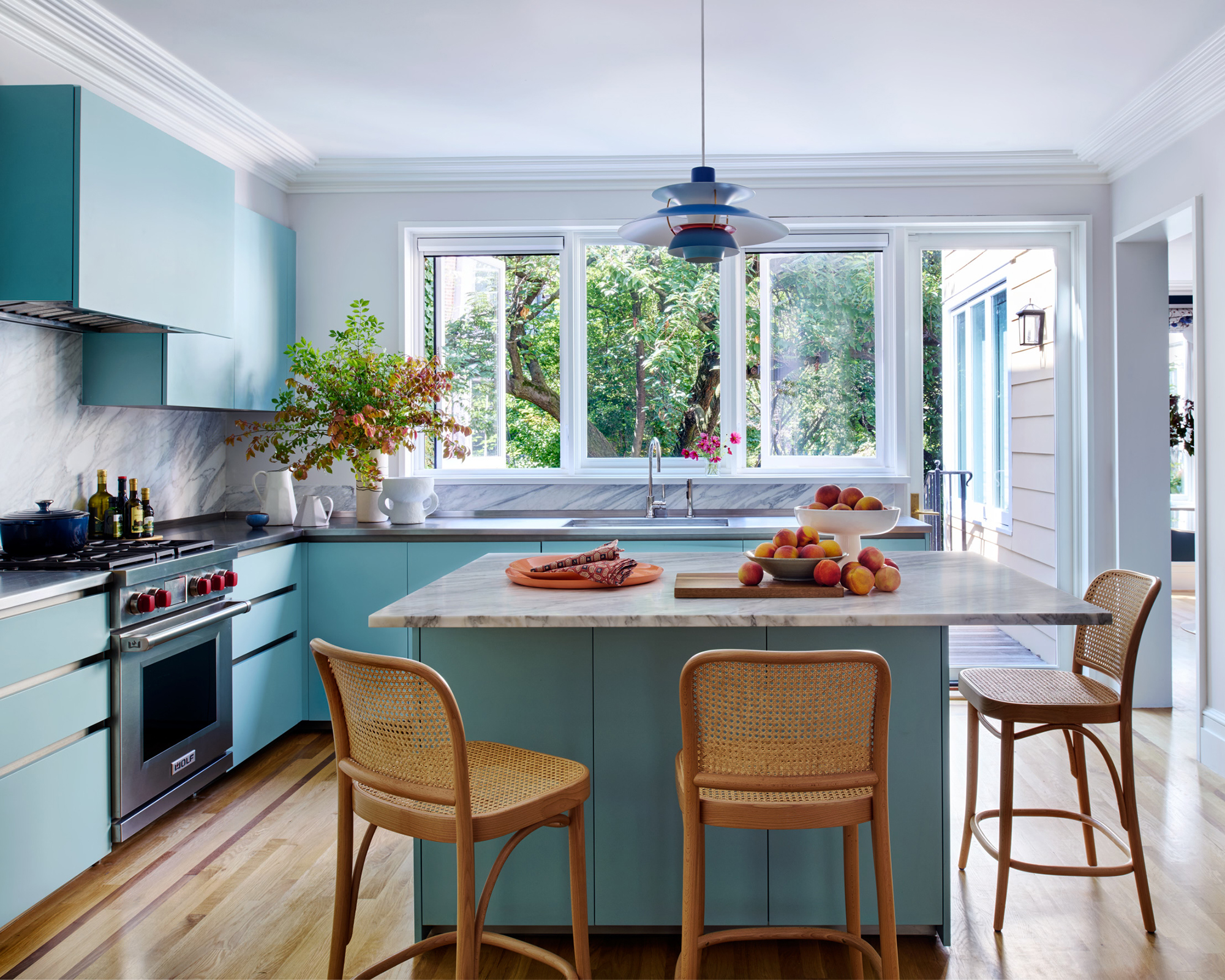 kitchen with blue cabinets and wood chairs around an island with a white top