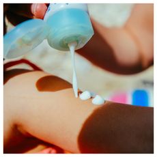 white woman applying sunscreen on the beach, close up shot