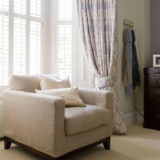 window with designed curtain cream colour sofa and cloth hanger