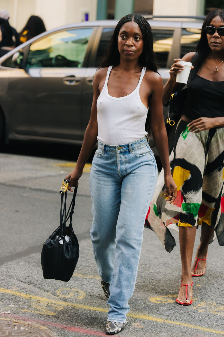 woman wearing a white tank and jeans with a black bag street style