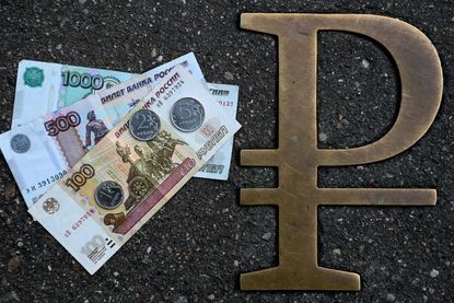 A photo of Russian ruble banknotes and coins next to a ruble symbol