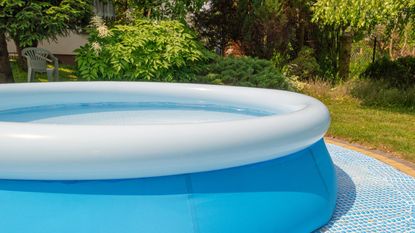 A blue inflatable pool in a green garden