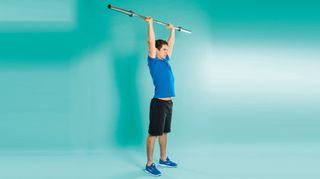 Man demonstrates the midway position of the push press exercise using an empty Olympic barbell
