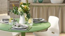 a dining table painted in green and set with flowers and place settings