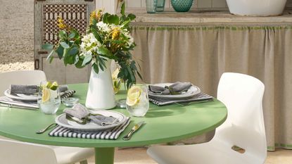 a dining table painted in green and set with flowers and place settings