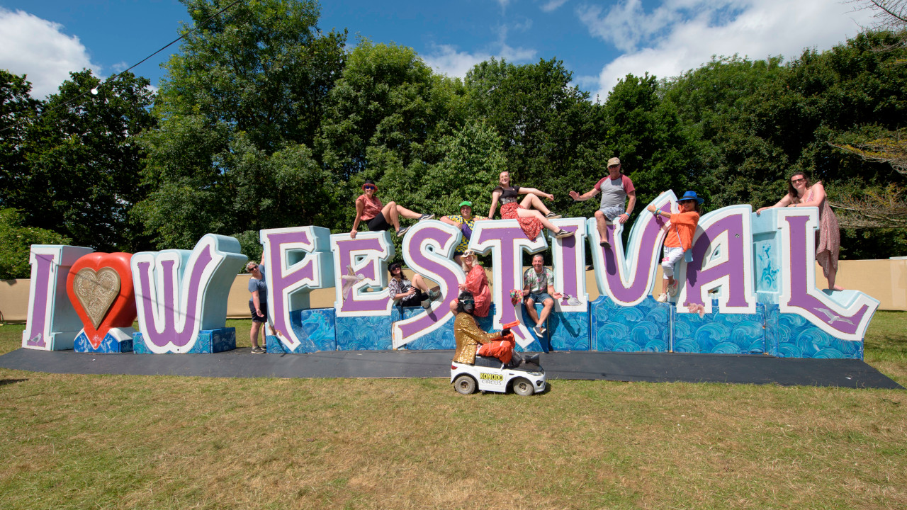 People on top of a large Isle Of Wight Festival sign in 2024