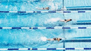 Three people lane swimming in a pool