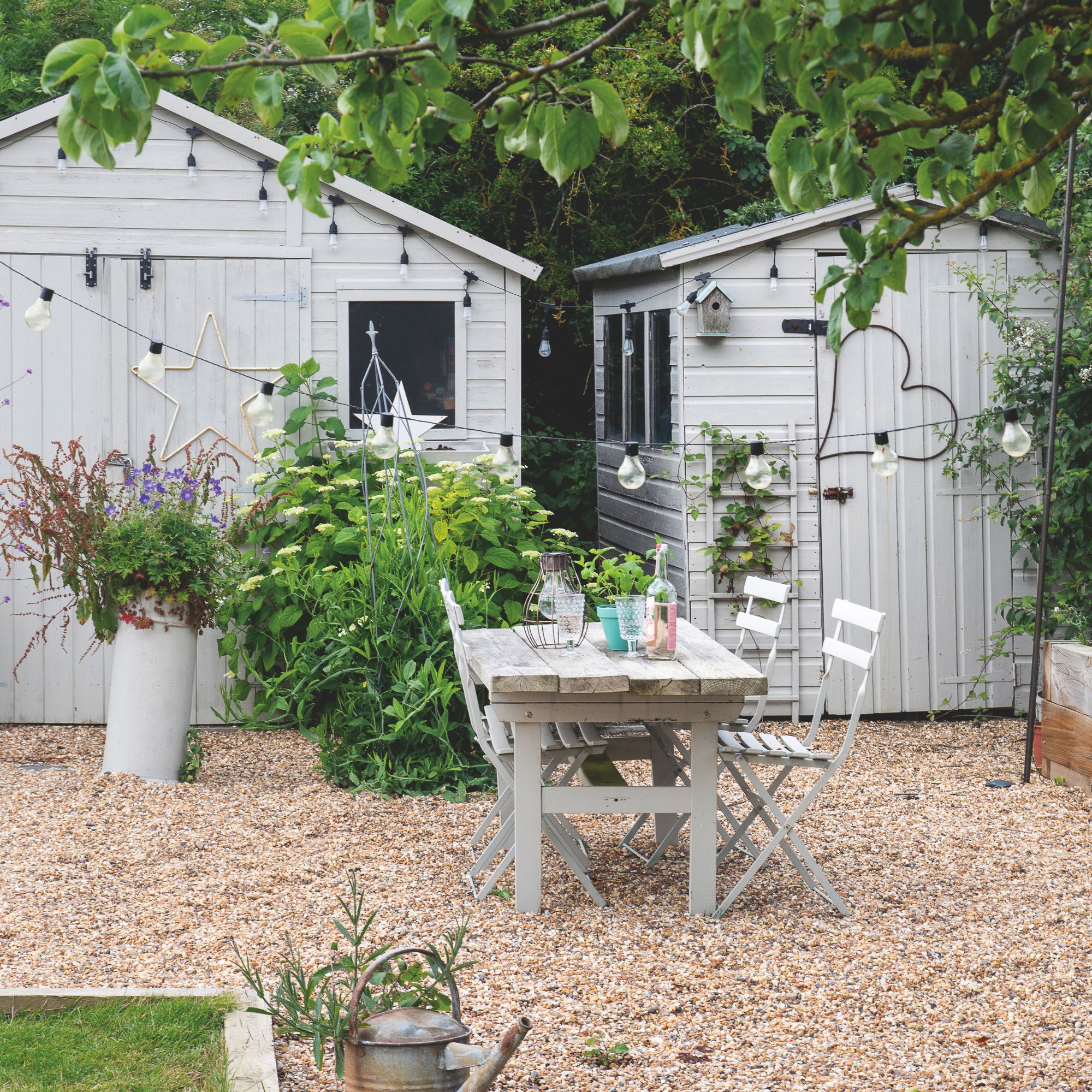 Gravel garden with two grey sheds at the back