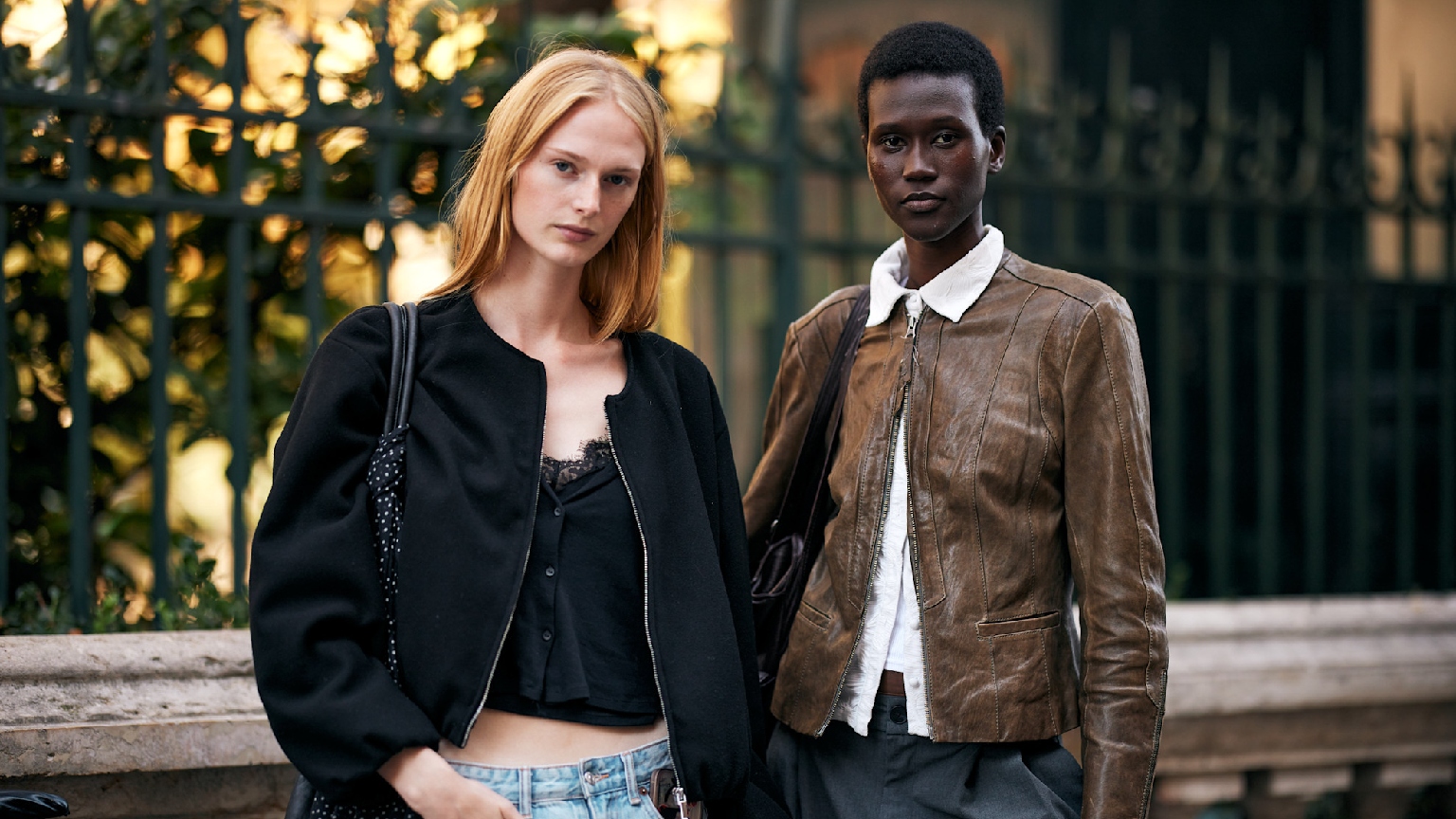 two women wearing a black jacket and a brownjacket with jeans