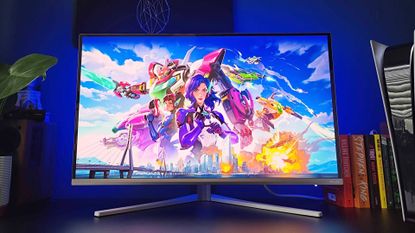 Philips Evnia 32M2N8900 monitor on black desk with ambilights illuminating back wall and Overwatch artwork on screen.