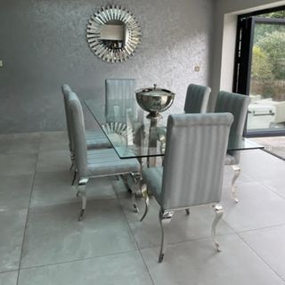 grey dining room with glass dining table and grey chairs with silver legs