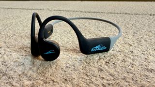 The h2o audio tri run bone conduction headphones on a stone surface