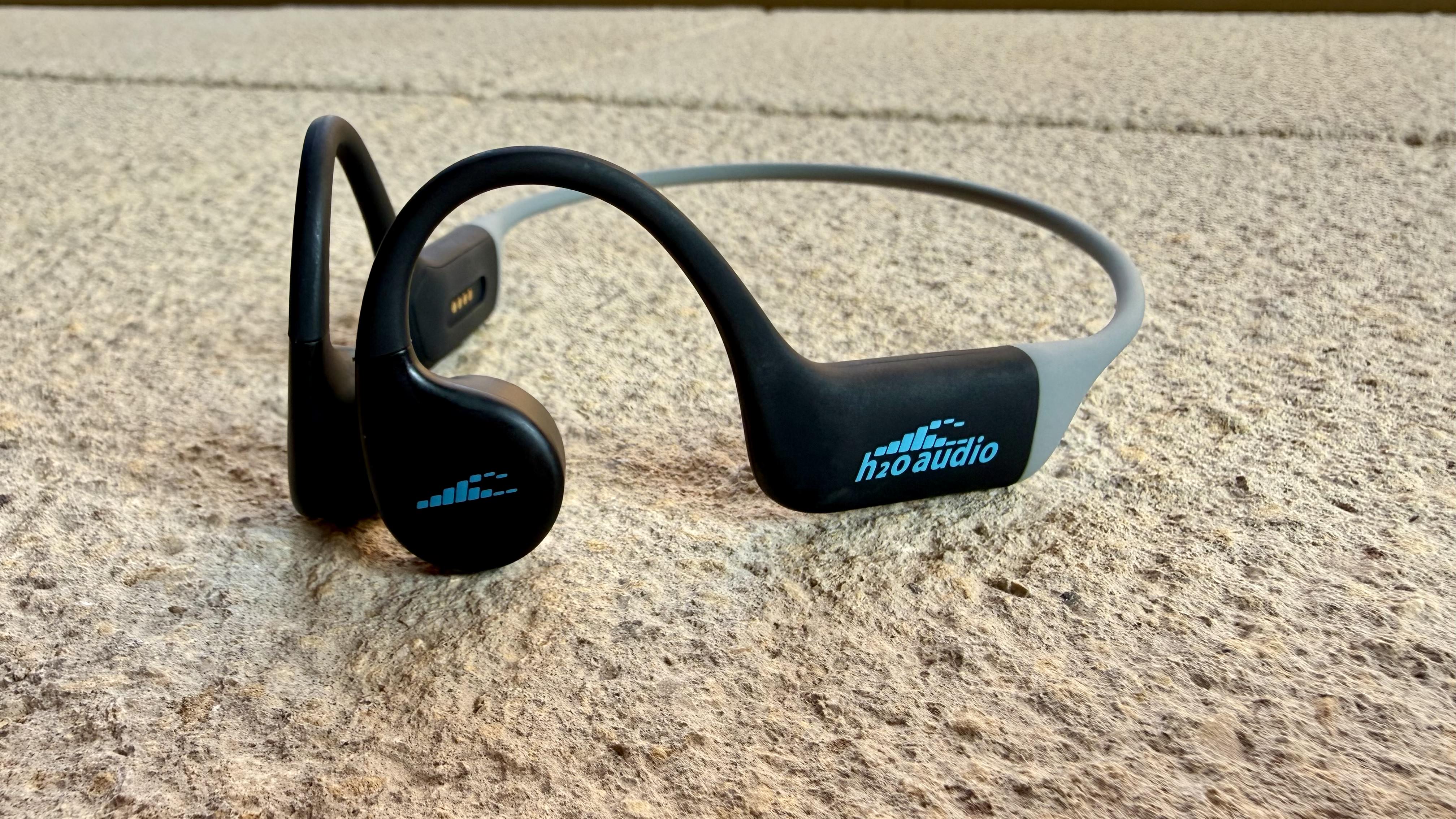 The h2o audio tri run bone conduction headphones on a stone surface