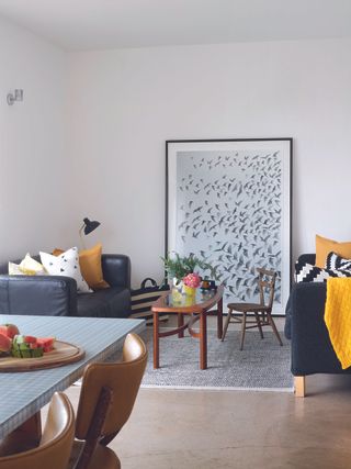 Open plan living room with black sofas and large artwork