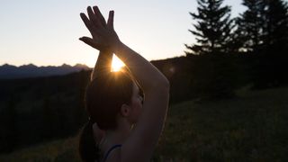 Julia Clarke with hands in prayer at sunrise on Vail mountain