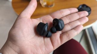 JLab Work Buds wireless earbuds with detachable microphone held in hand.