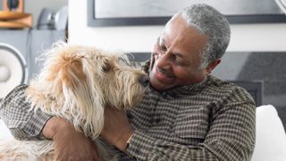 Senior man hugging his dog on couch