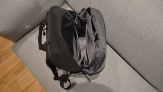 A Lo & Sons Hanover Deluxe 2 backpack open on a gray couch