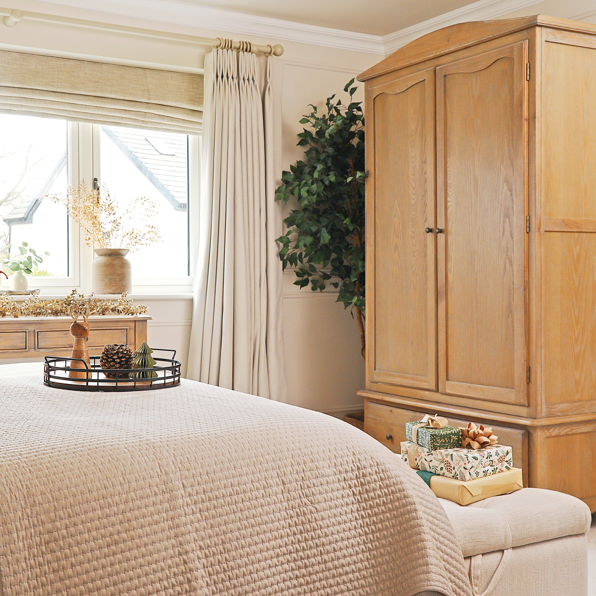 a neutral bedroom with large wooden wardrobe decorated for Christmas with presents and candles