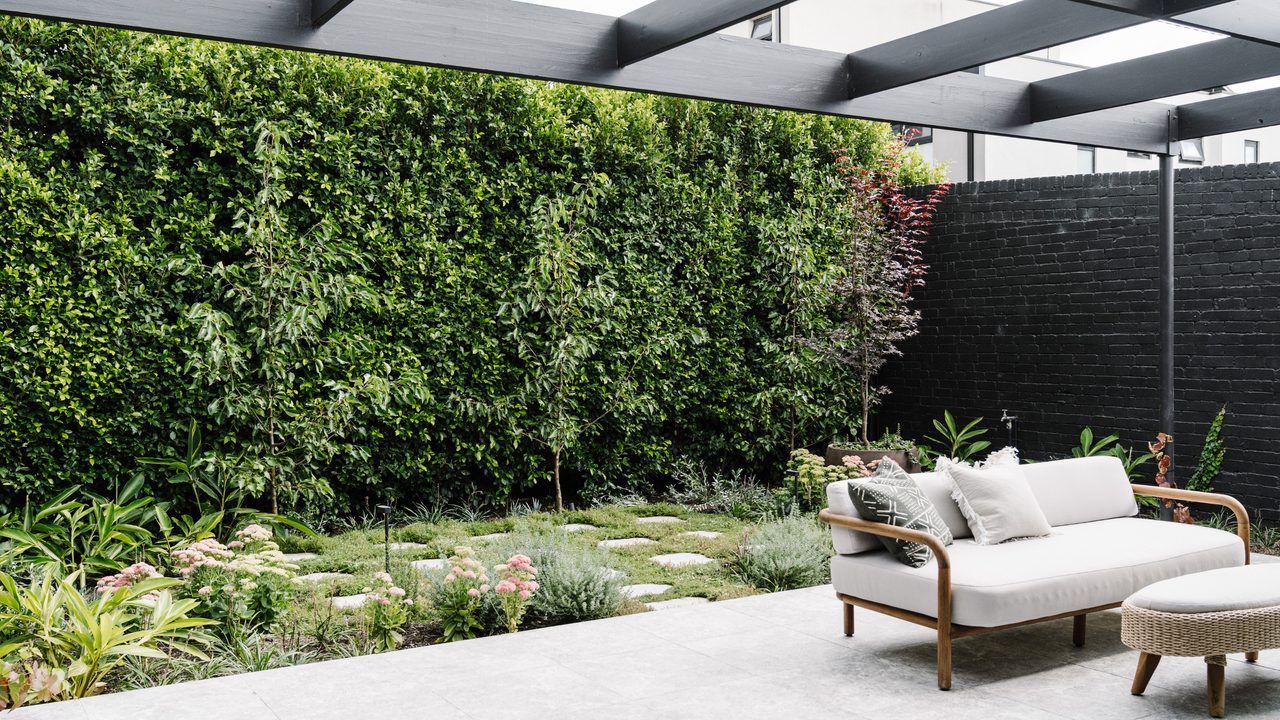 A shady backyard with flowers next to a patio