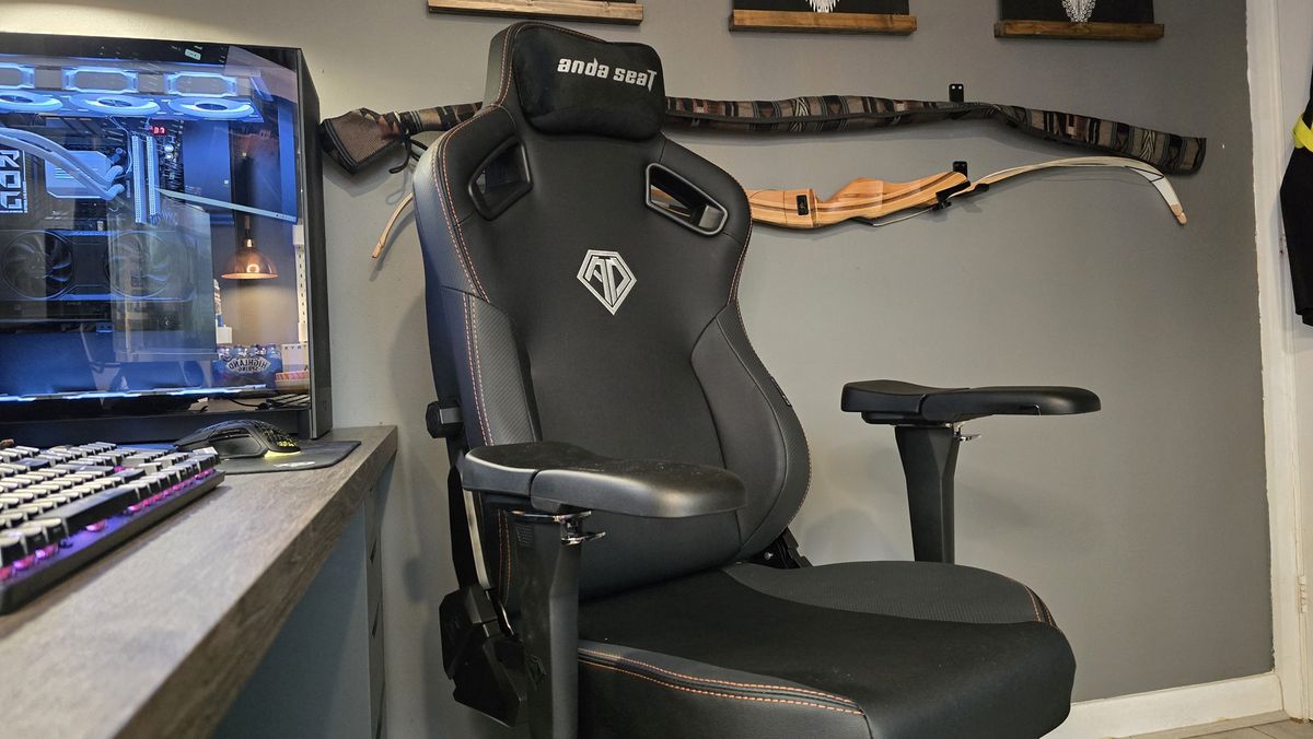 The AndaSeat Kaiser 3 Pro next to a gaming desk and a wall.