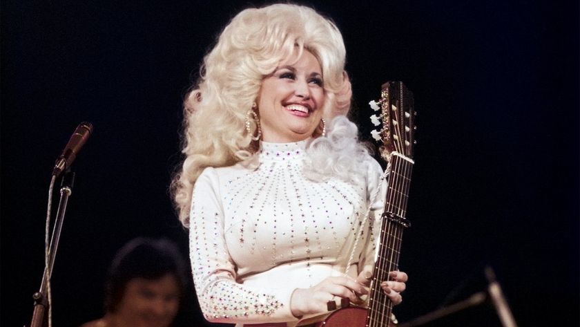 Dolly Parton performs onstage with her guitar in the mid 1970s