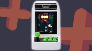 Sega Astro City Mini V arcade machine with navy and orange GamesRadar+ backdrop with plus symbols.
