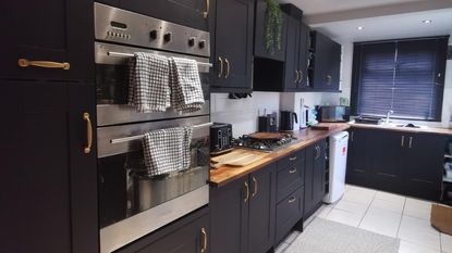 black kitchen cabinetry with neutral floor tiles and patterned rug