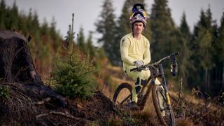Loic Bruni wearing pastel yellow Specialized kit, sat on a mountain bike, with a Red Bull full face helmet lifted up to reveal his face 