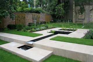 walled garden with contemporary paving and a central water feature
