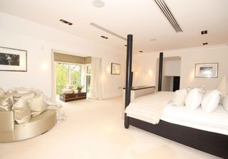 white bedroom with linen couch and black bed