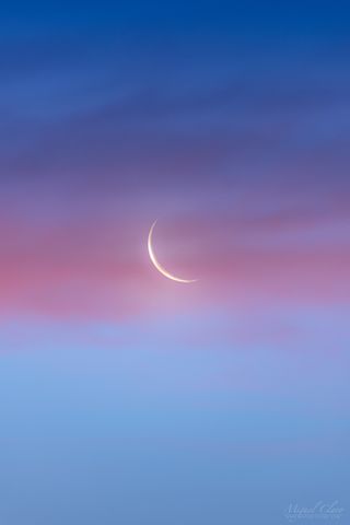 The waning crescent moon rises at dawn against a beautiful blue twilight and behind a pink band of clouds in this photo captured by astrophotographer Miguel Claro in Portugal's Dark Sky Alqueva Reserve.