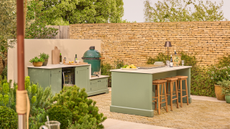 sage green outdoor kitchen with bar stools and a big green egg grill