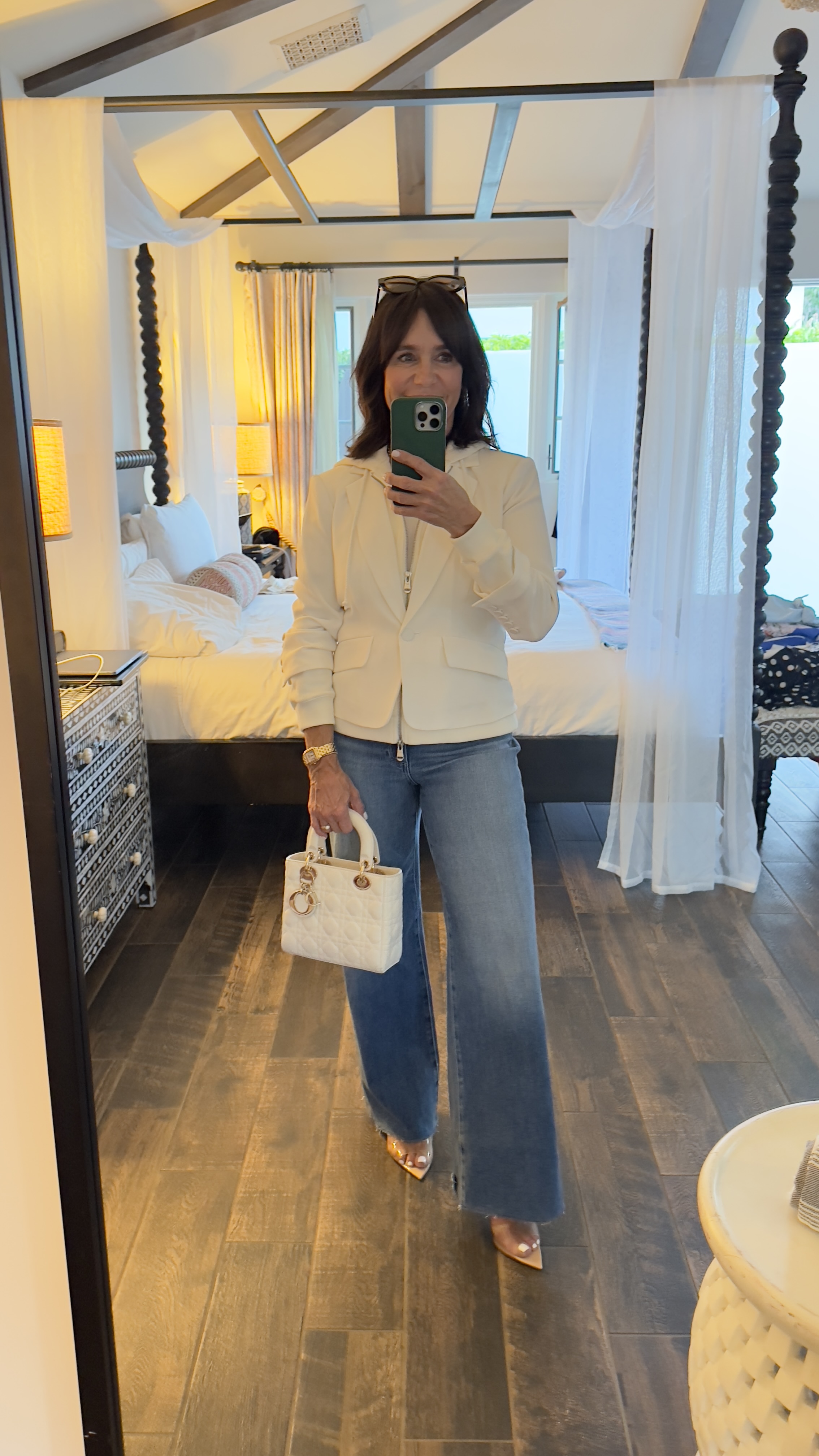 A former Nordstrom buyer wearing a white blazer and flared blue jeans.