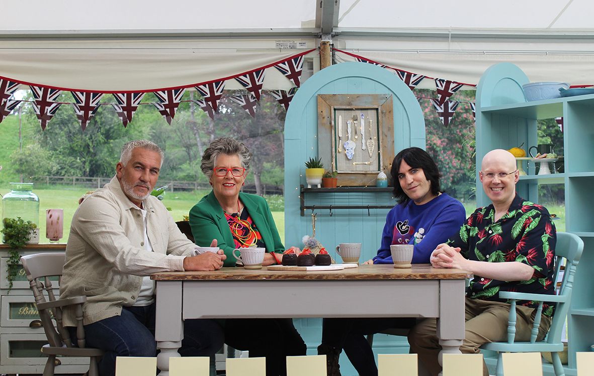 Celebrity Bake Off judges sitting around a table 