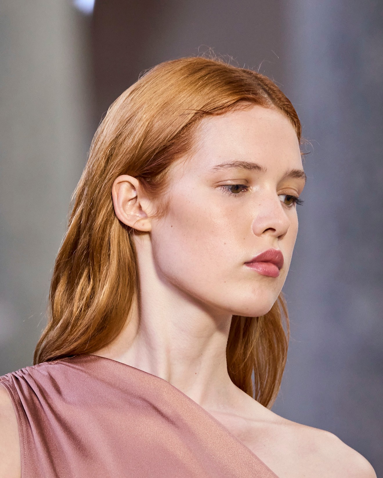 A model with red hair in a pink silk off the shoulder top