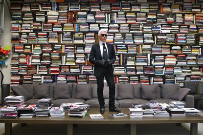 Karl Lagerfeld in front of shelves of books