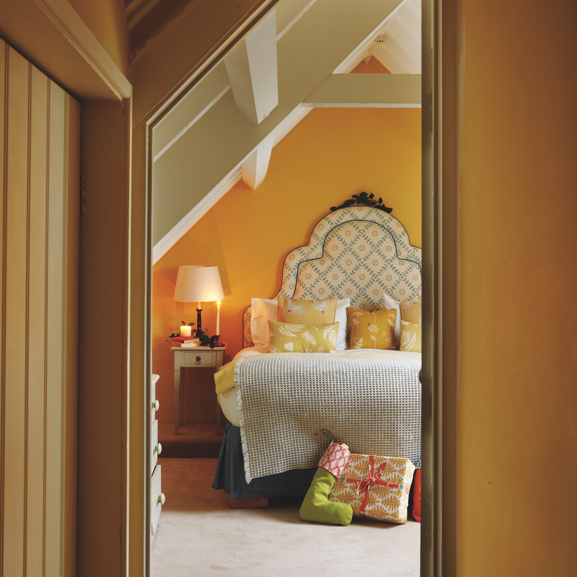 bedroom in eaves with yellow wall and upholstered bed