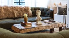 timber coffee table with antiques on top, olive green sofa and fur throw