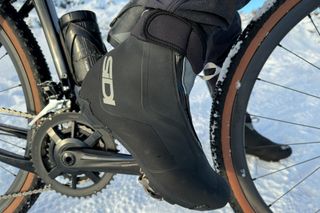 Close up a male rider's feet wearing Sidi Algor shoes riding a gravel bike in the snow