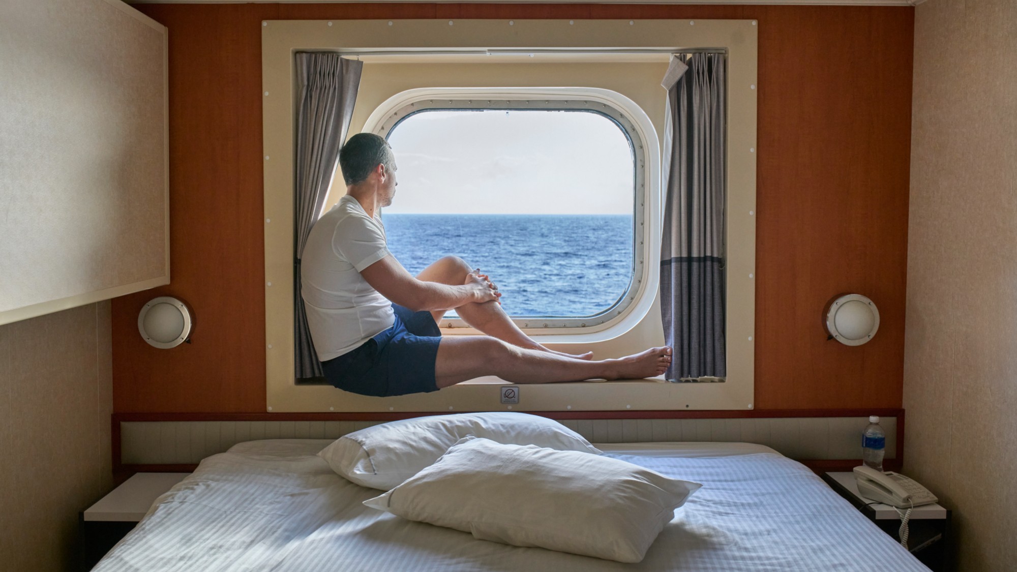 Man gazing at the ocean from a cruise ship cabin