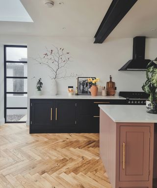 A pink and black kitchen with hardwood floors