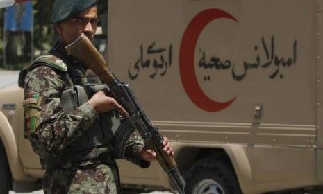 An Afghan National Army soldier patrols the gate of the military hospital next to an ambulance in Kabul