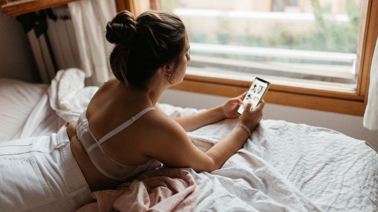 woman in bed on her phone