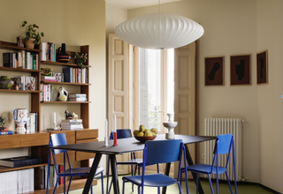 A dining room with cream walls, and electric blue chairs