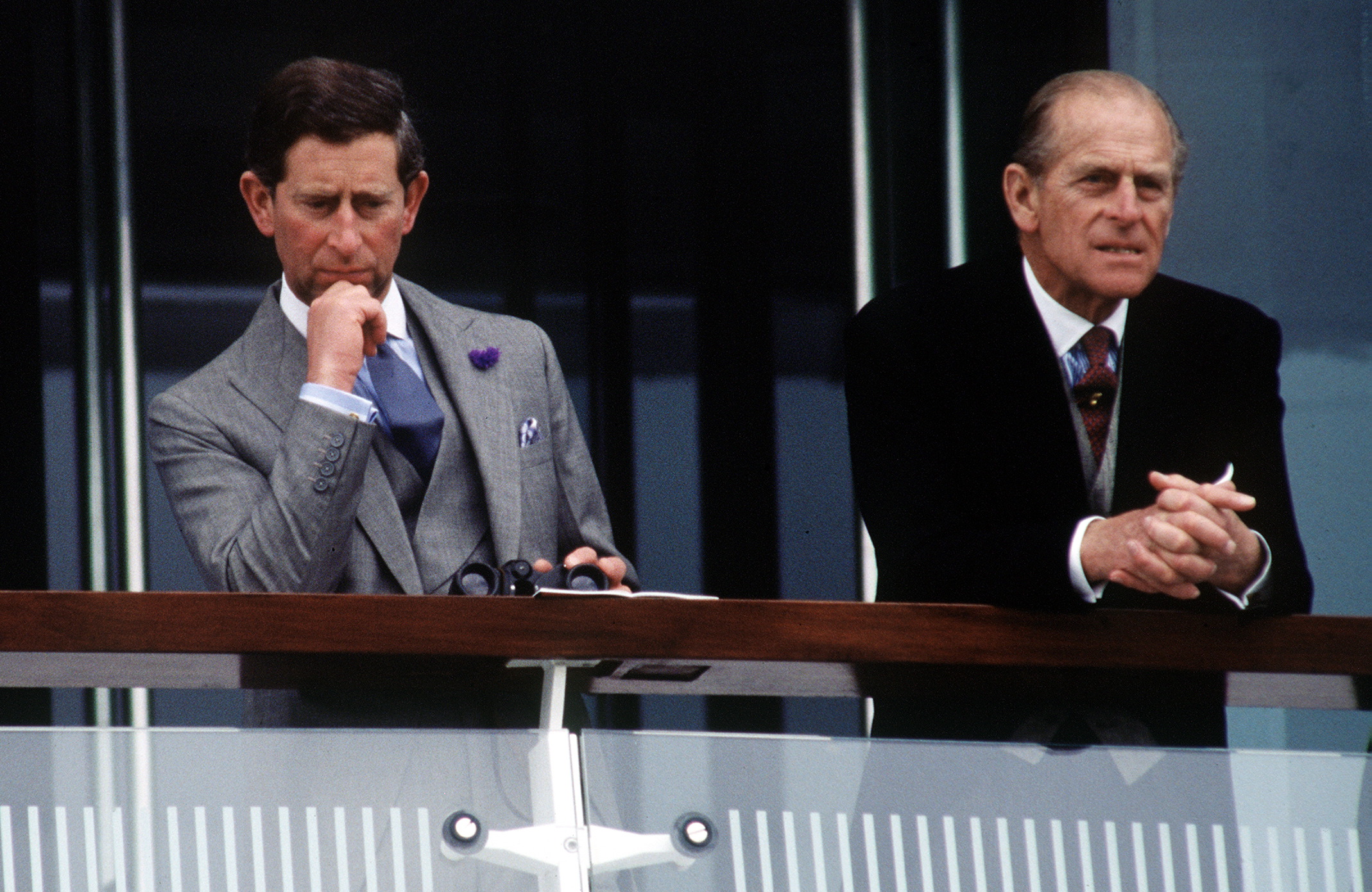 Prince Charles leans his chin on his hand next to Prince Philip, resting on a railing at the 1993 Epsom Derby