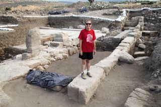 Archaeological dig leader Jodi Magness standing on a wall within the excavation site.