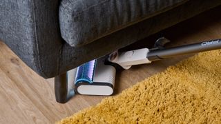 Shark Detect Pro cordless vacuum with headlights on as it goes underneath a sofa