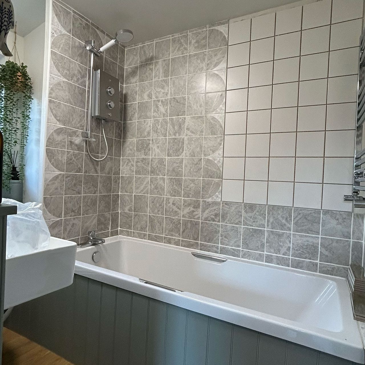 Bathroom with teal panelled bath and scalloped grey tile pattern on walls