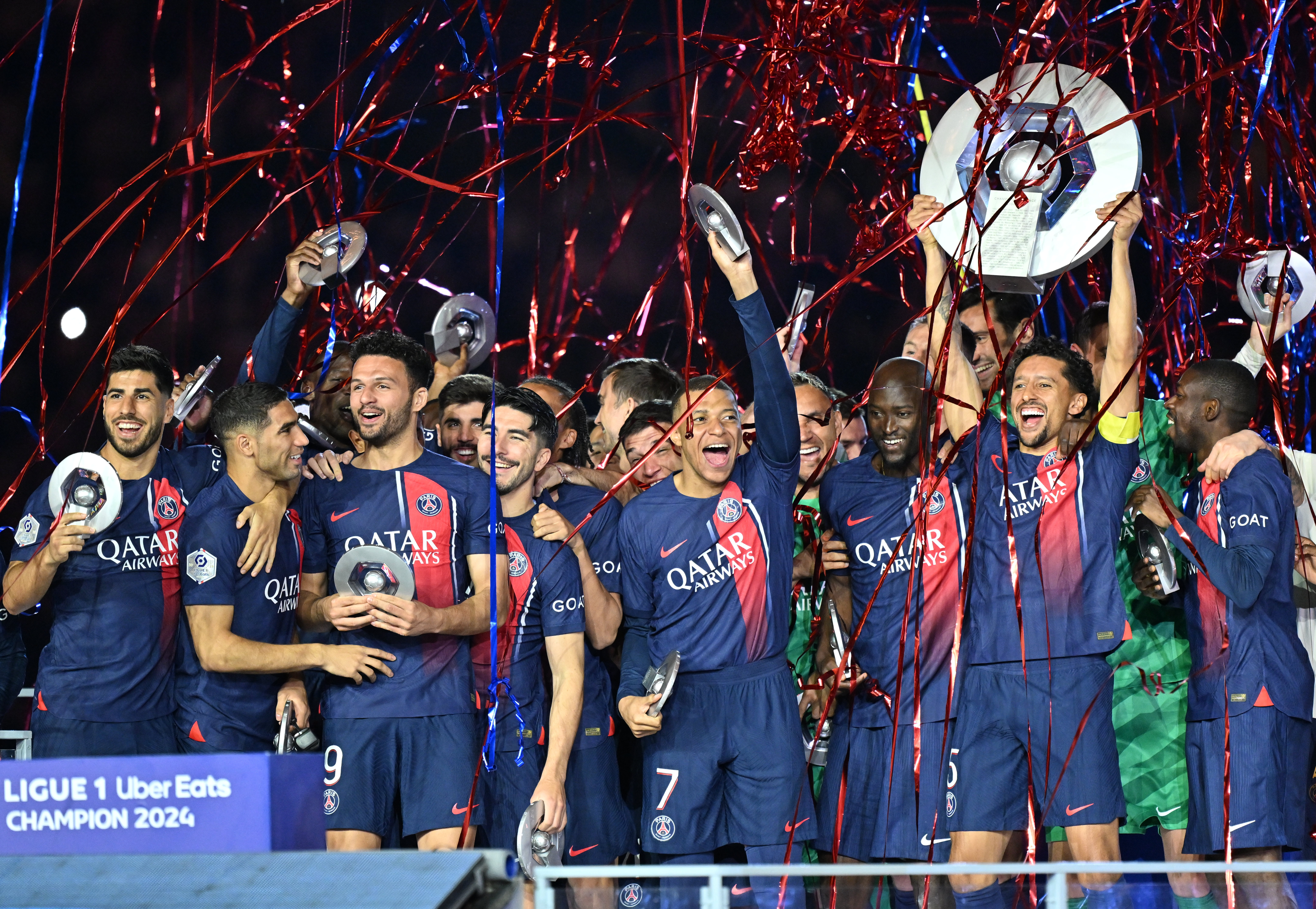 Paris Saint-Germain players celebrate with the Ligue 1 trophy after winning the title in 2023/24.